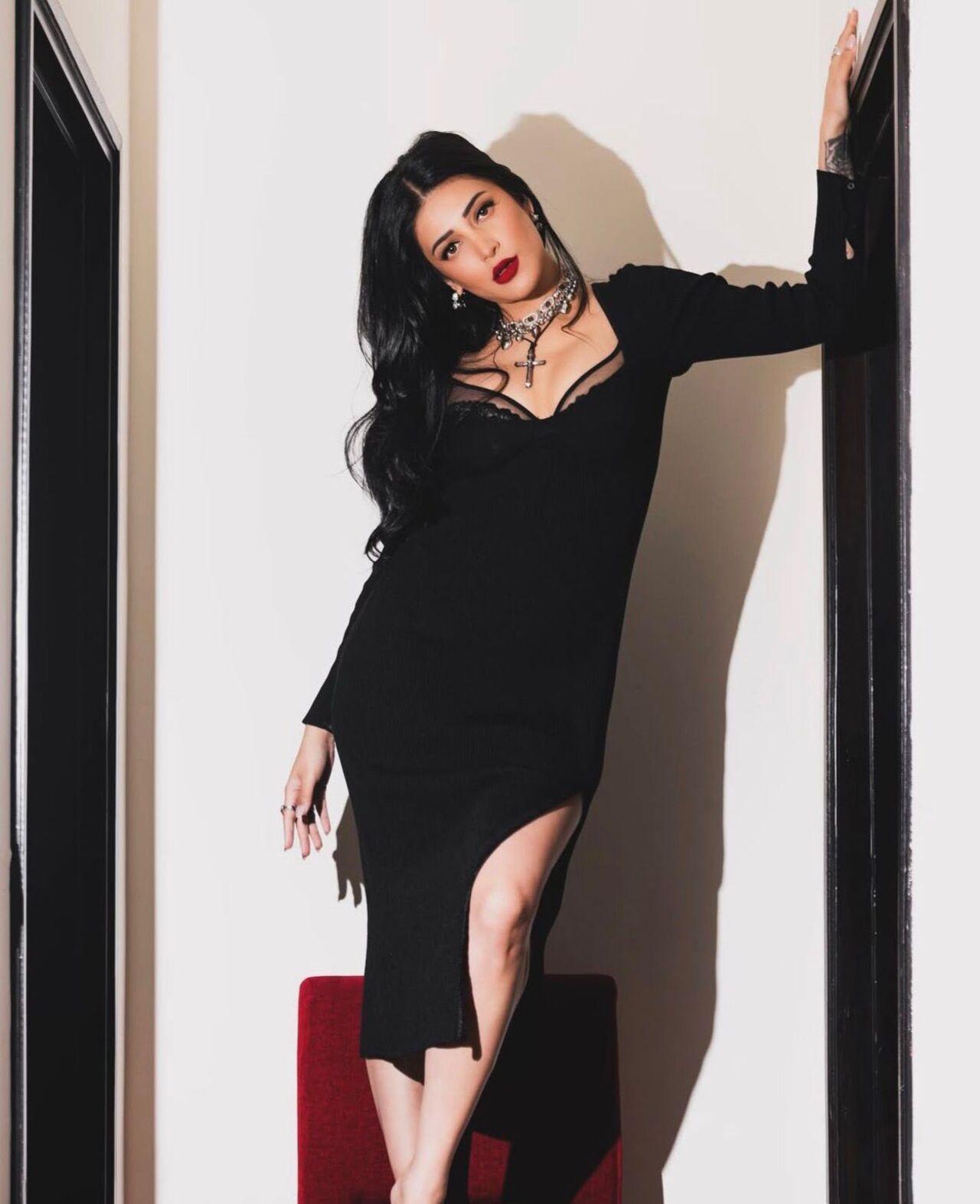 Cross motifs, stacked chains, chokers, and bold rings sharpen this black dress, with each accessory carrying a sense of symbolism. It blends dark romance with rockstar rebellion.